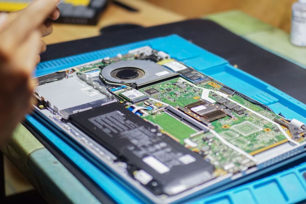 Technician repairing a laptop's internal components on a workbench